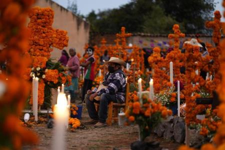 Relatives prepare to spend the night next to the tomb of their loved ones during Day of the Dead festivities at the the Arocutin cemetery in Michoacan state, Mexico, Monday, Nov. 1, 2021. In a tradition that coincides with All Saints Day and All Souls Day, families decorate the graves of departed relatives with flowers and candles, and spend the night in the cemetery, eating and drinking as they keep company with their deceased loved ones. (AP Photo/Eduardo Verdugo)